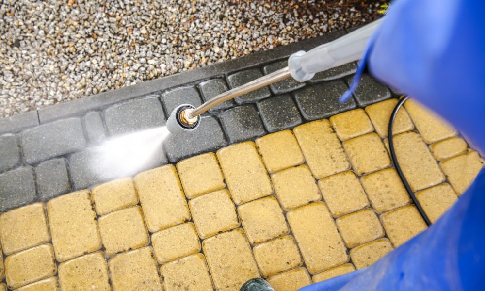 Driveway Bricks Pavement Washing Using Pressure Washer. Closeup Photo.